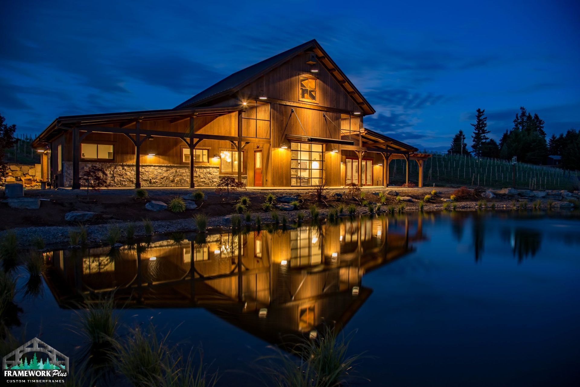 A large house is lit up at night and is reflected in a pond.