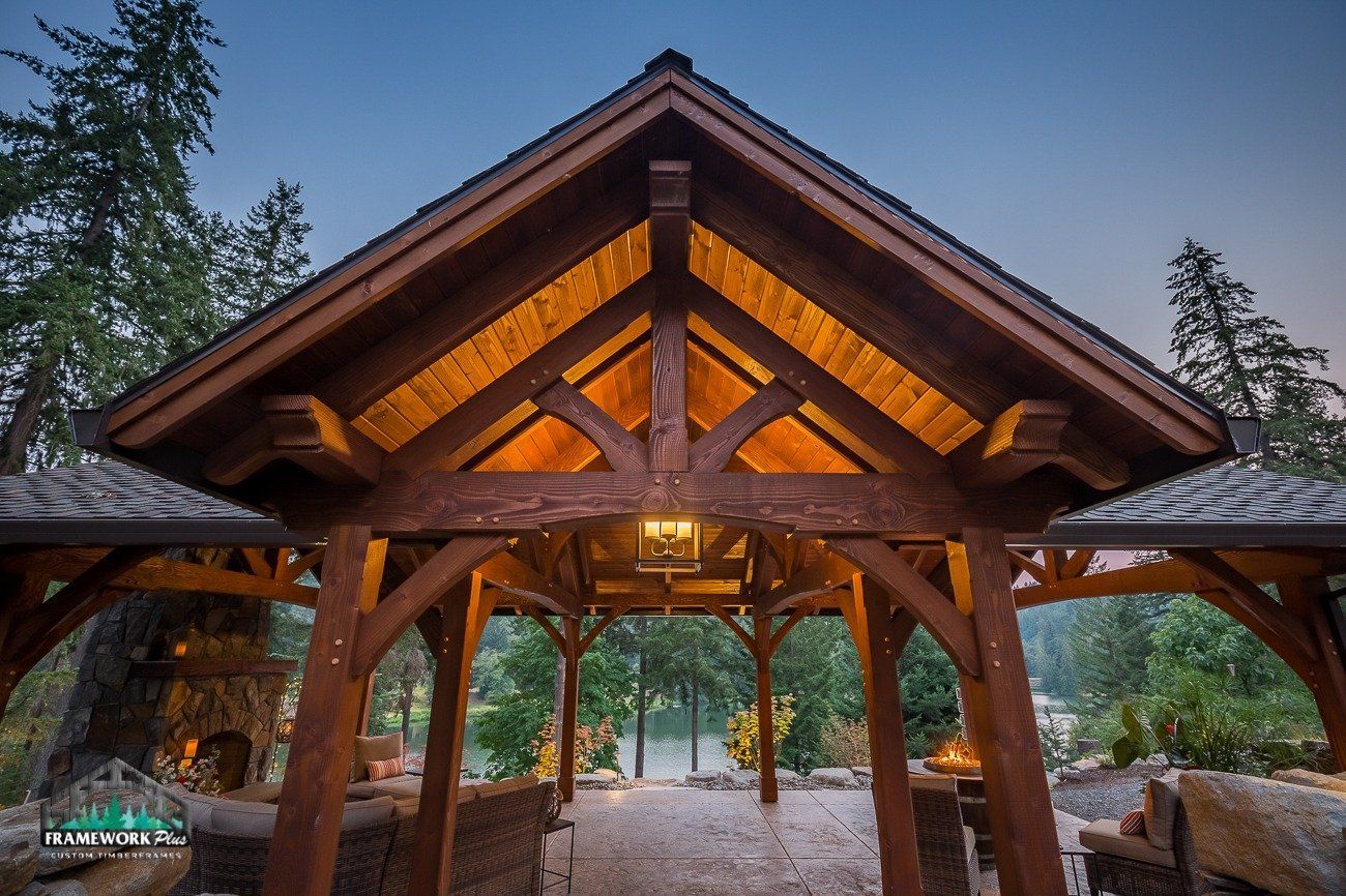 A wooden gazebo with a roof that is lit up at night.