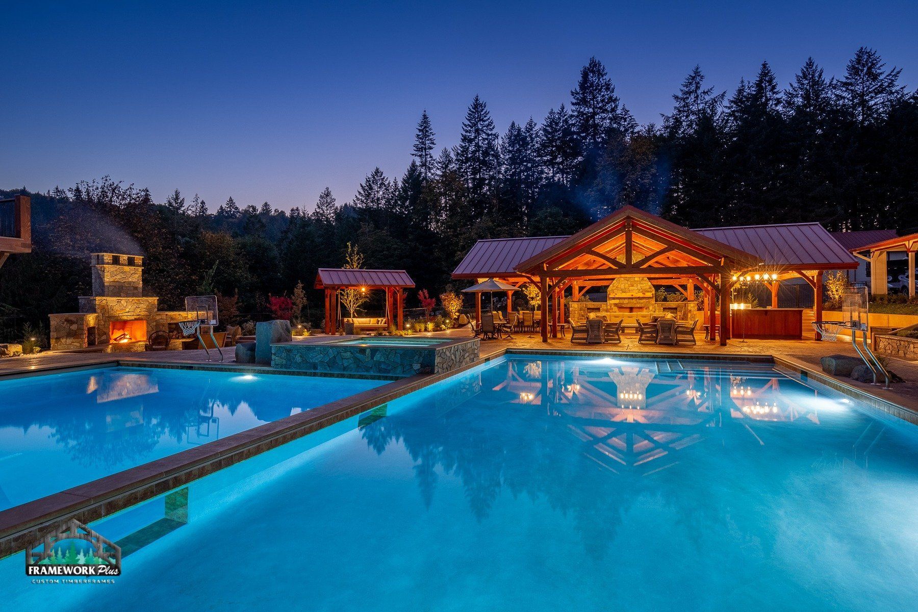 A large swimming pool is lit up at night with a gazebo in the background.