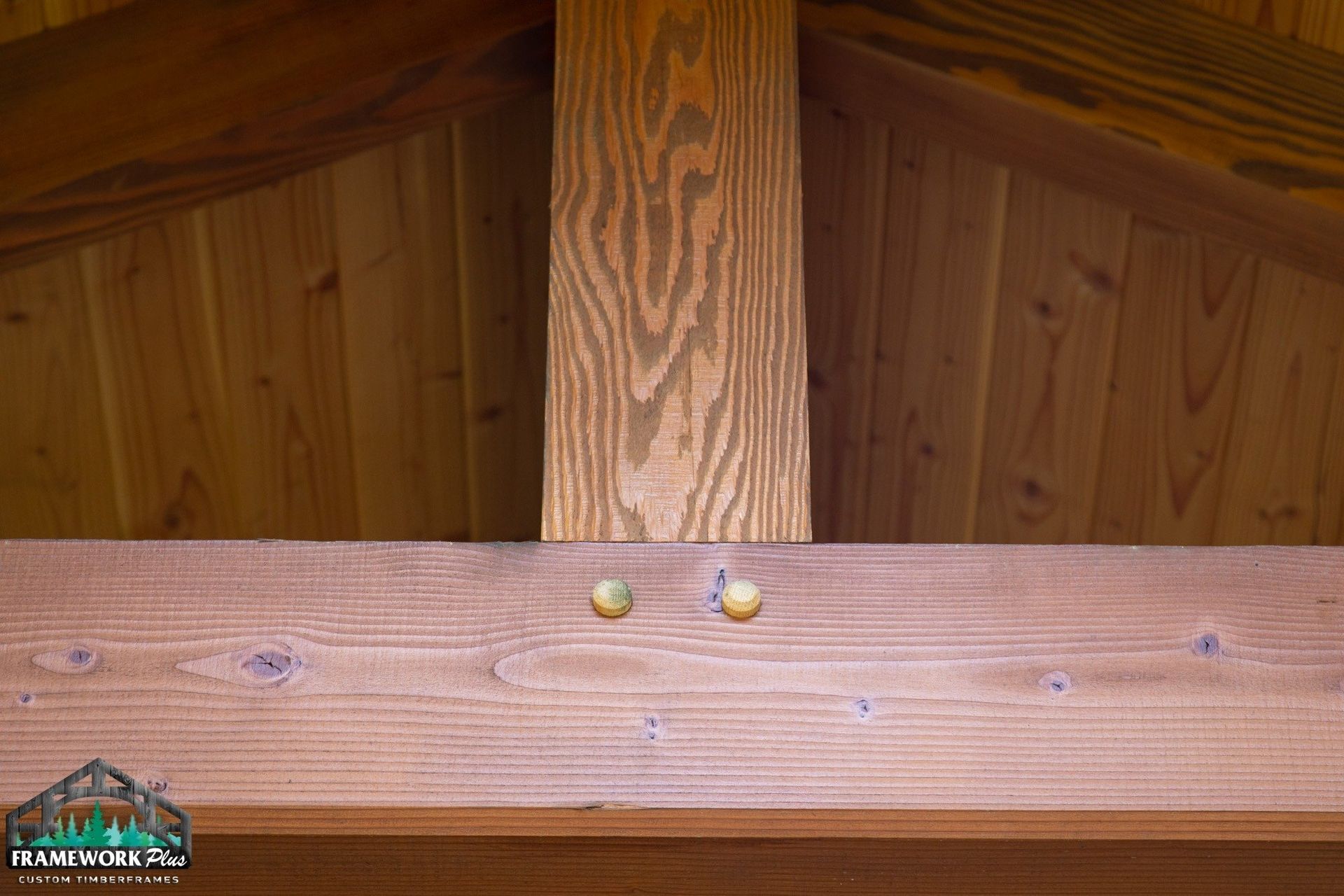 A close up of a wooden beam with two screws in it.