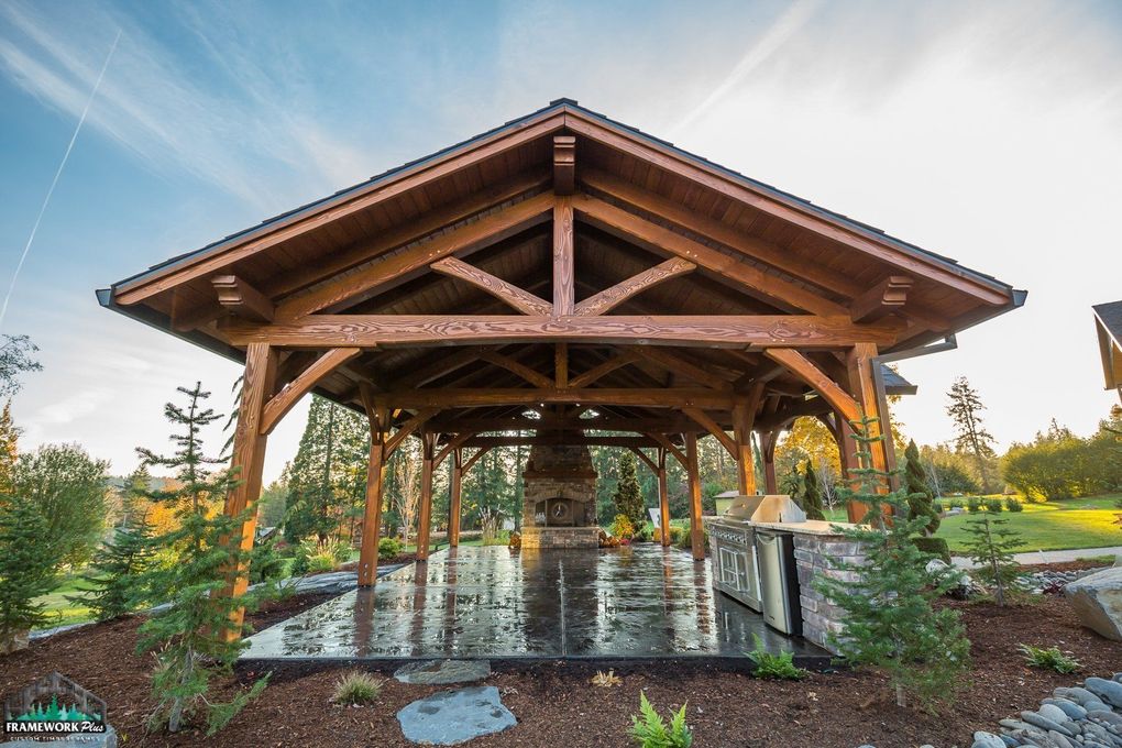 A wooden pavilion with a fireplace and a grill