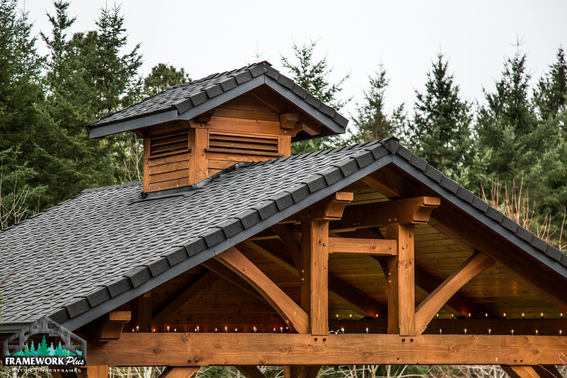 A wooden structure with a roof that is surrounded by trees.