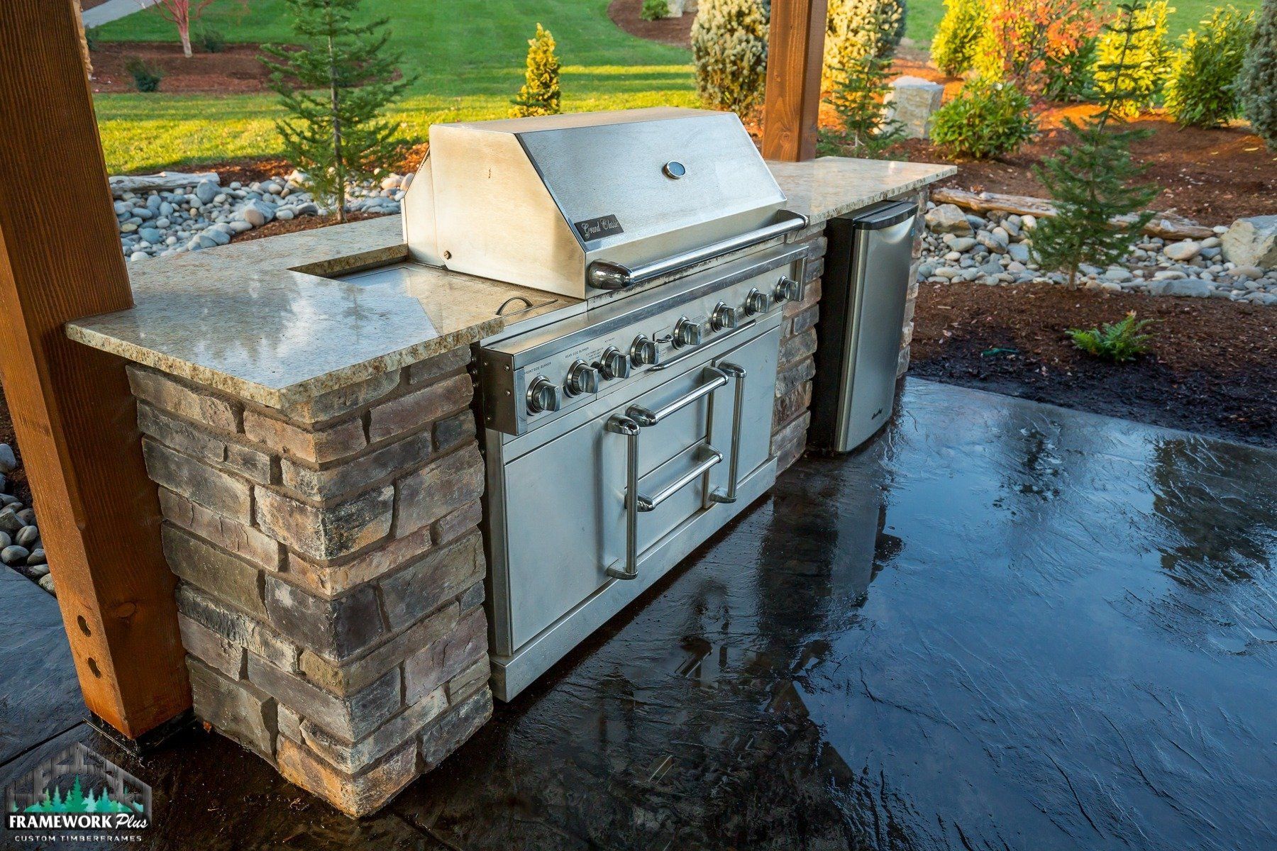 An outdoor kitchen with a grill and a dishwasher.