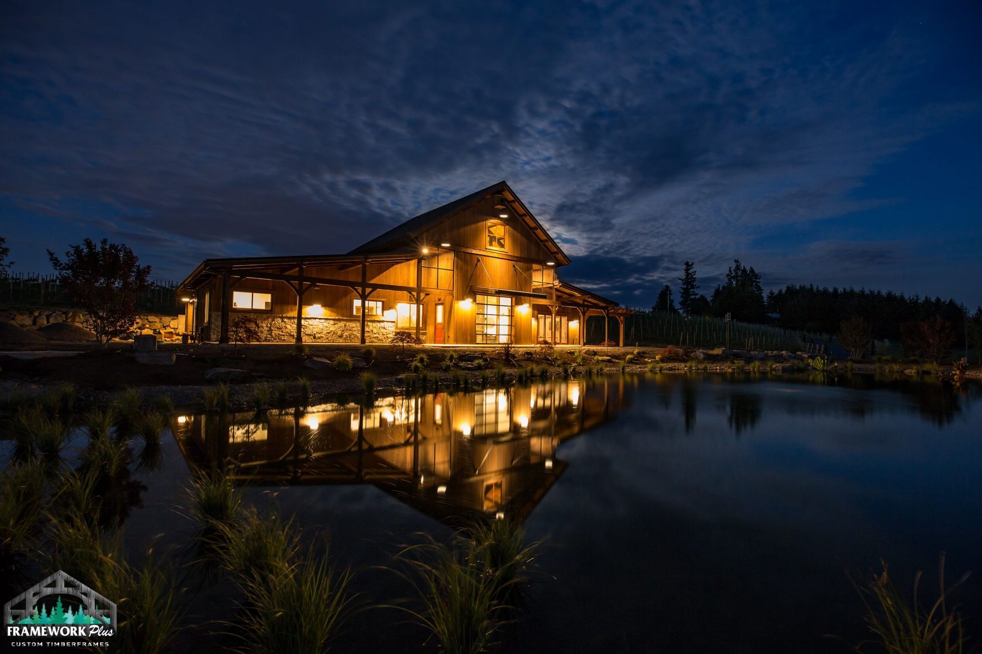 A large house is lit up at night and reflected in a pond.