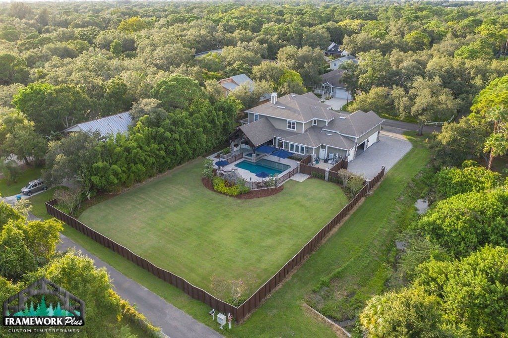 An aerial view of a large house with a pool in the backyard surrounded by trees.