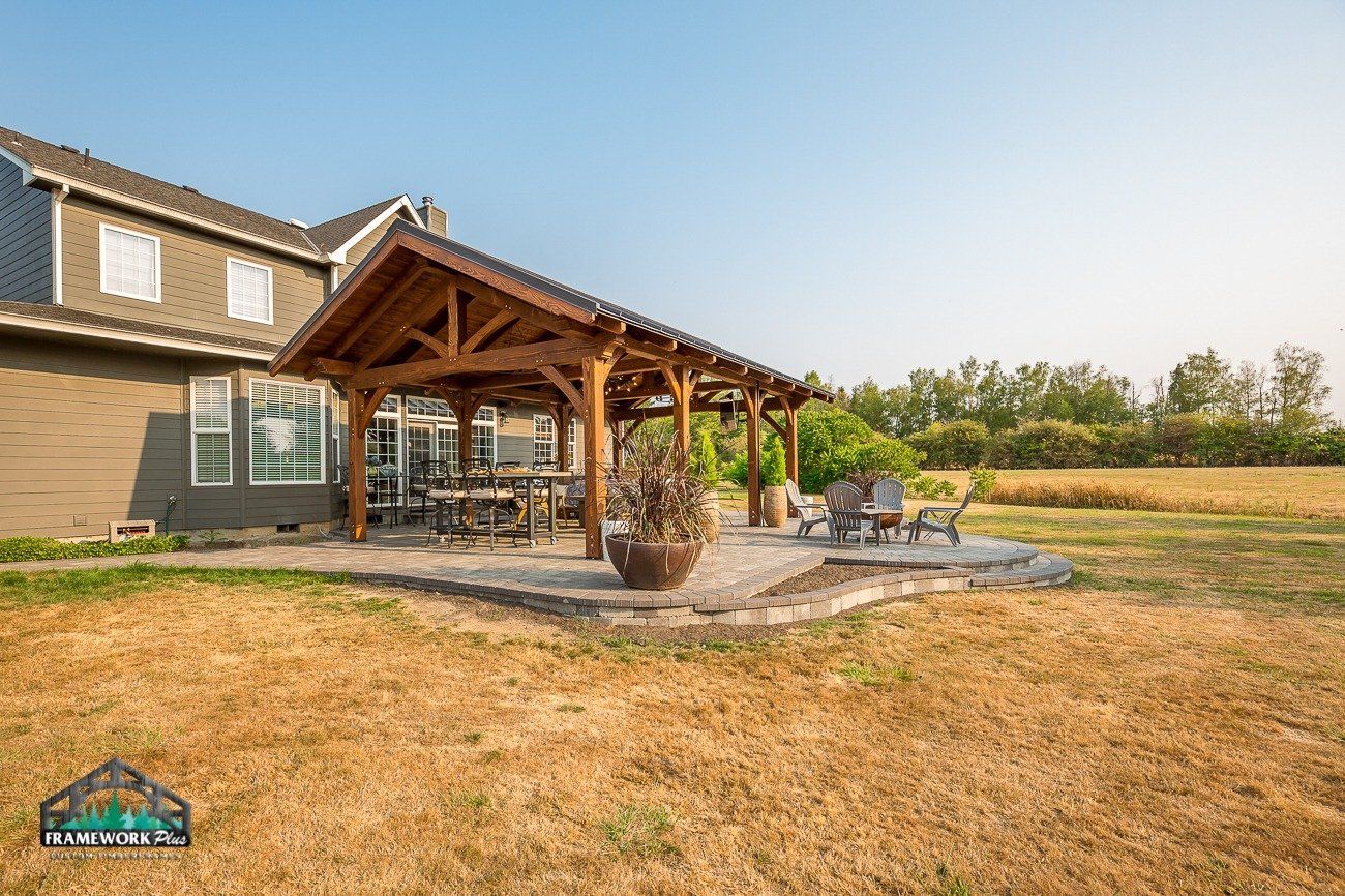 A large house with a wooden pavilion and patio in front of it.