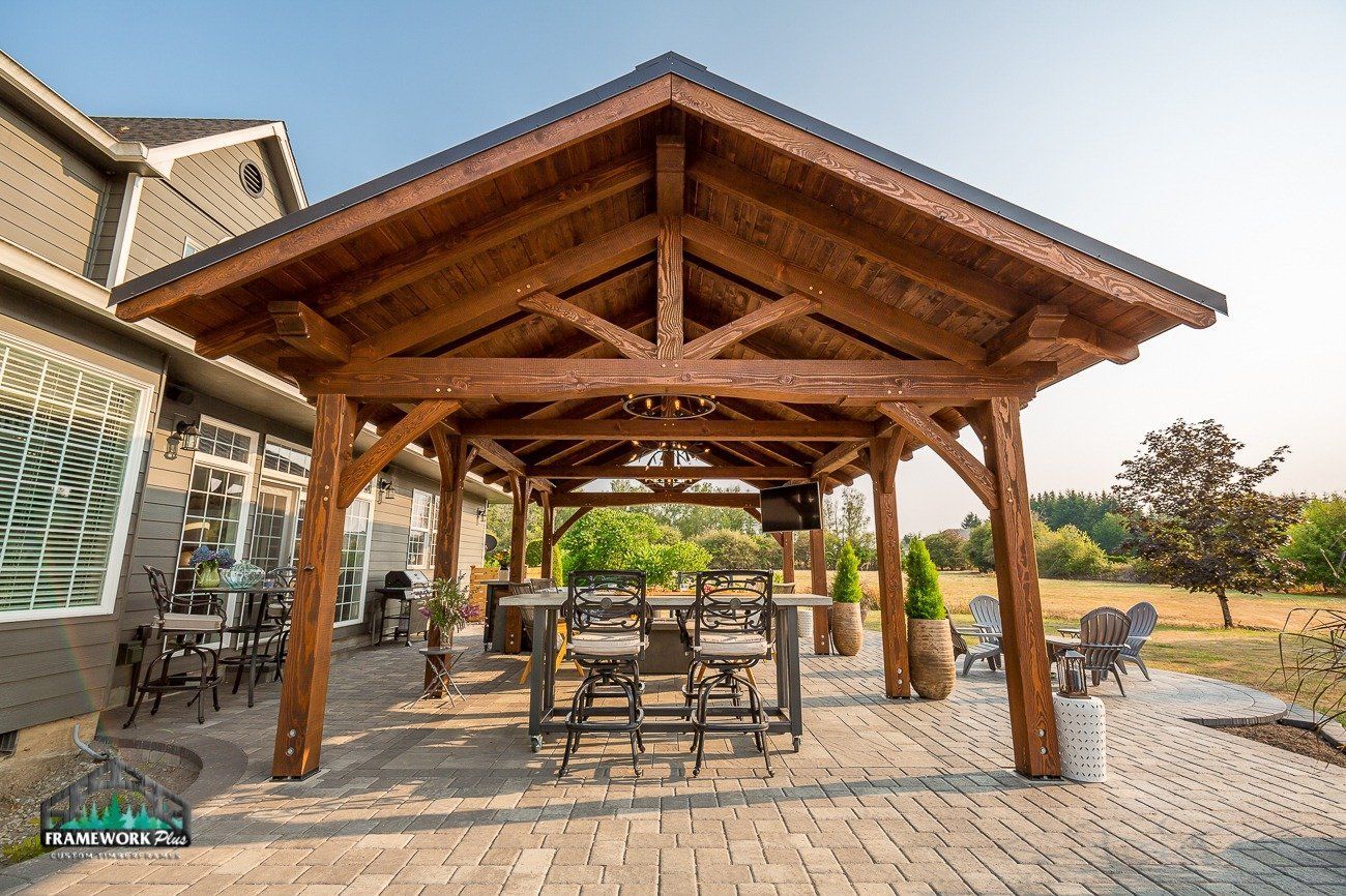 A wooden pavilion with a table and chairs underneath it.