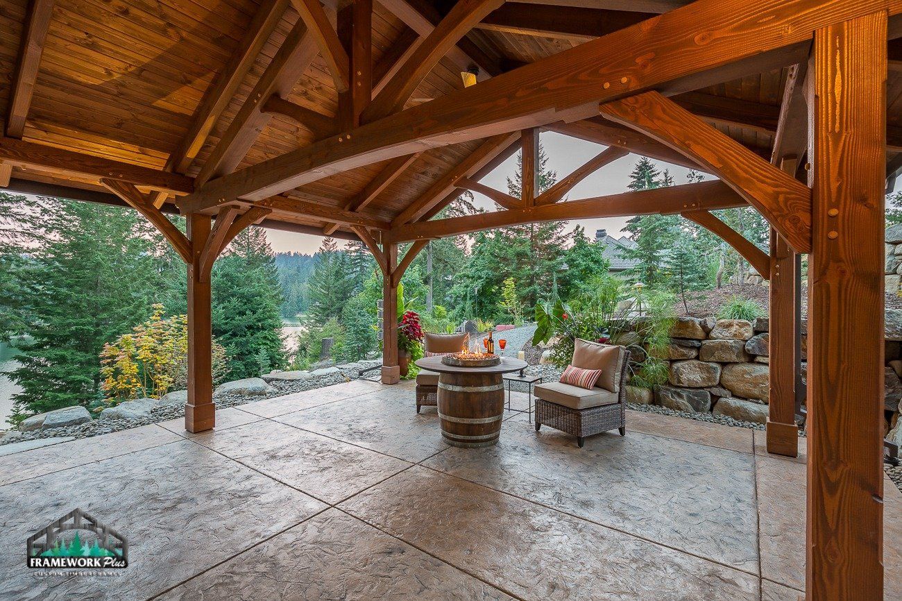 A wooden gazebo with a fire pit in the middle of it.