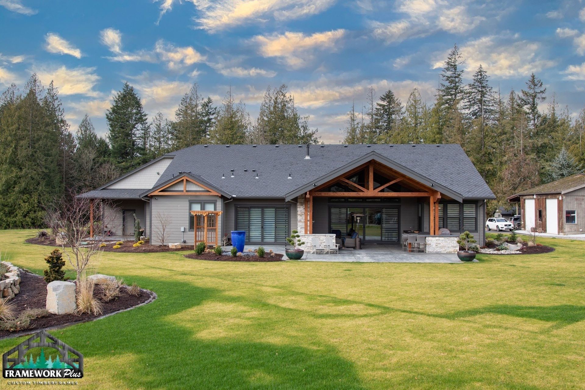 A large house with a gray roof is sitting on top of a lush green field.