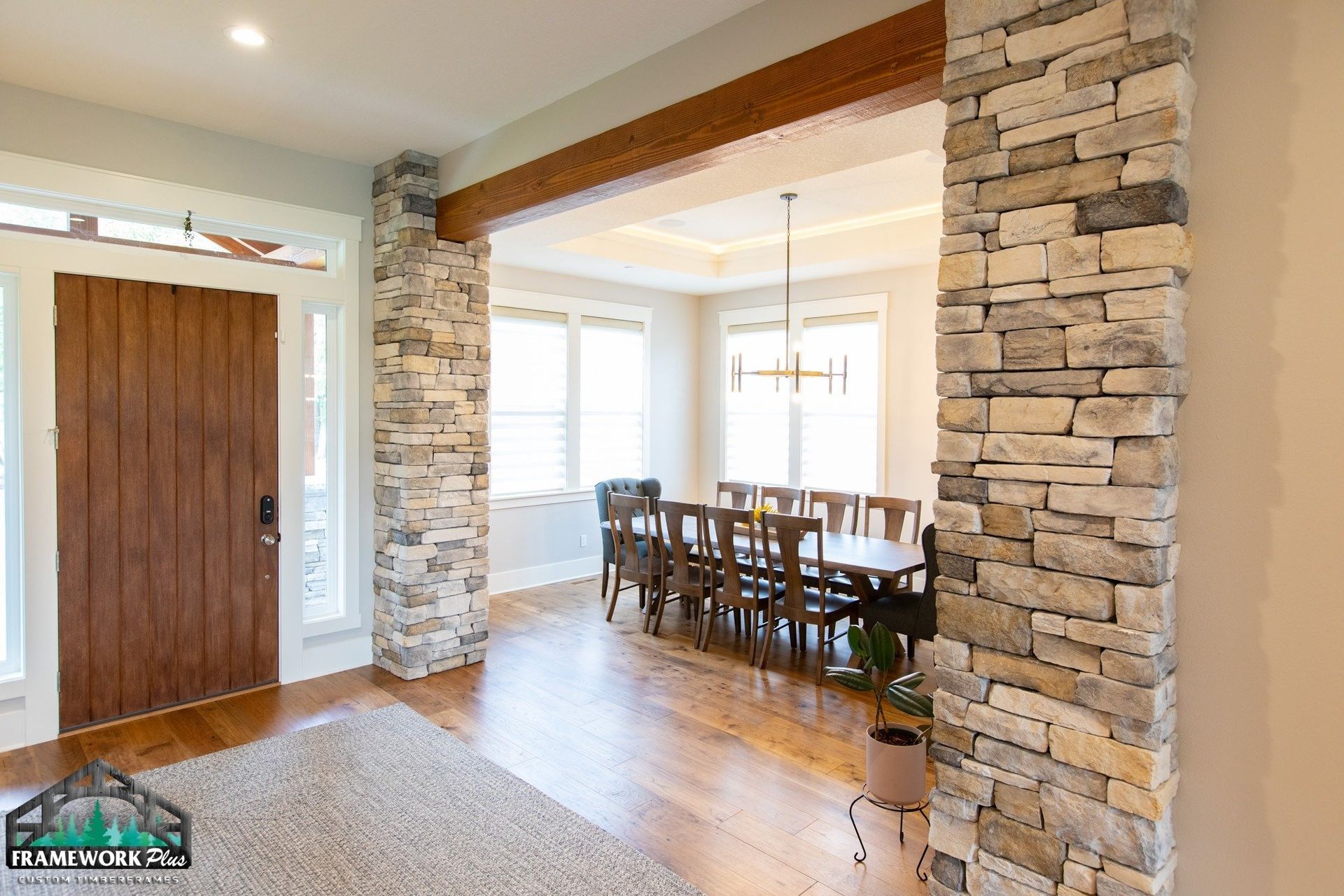 A dining room with a stone wall and a wooden table and chairs.