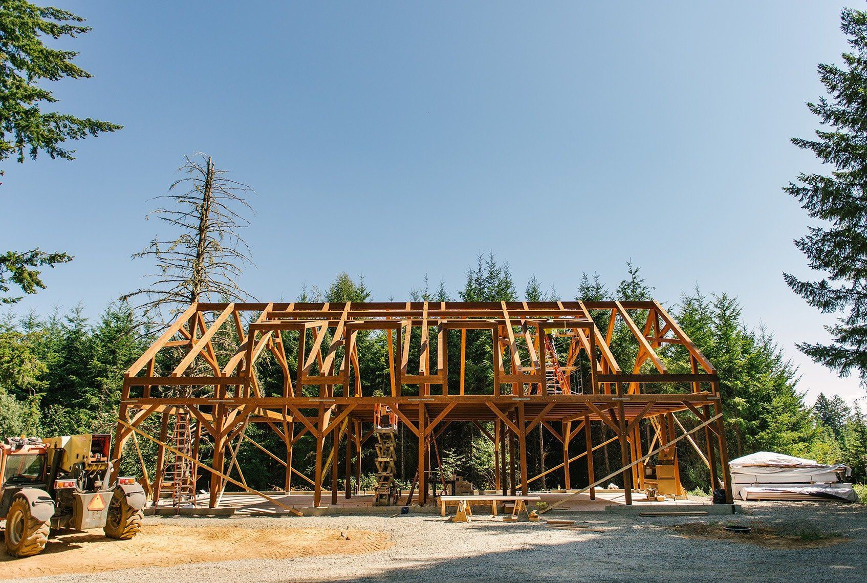 A large wooden structure is being built in the middle of a forest.