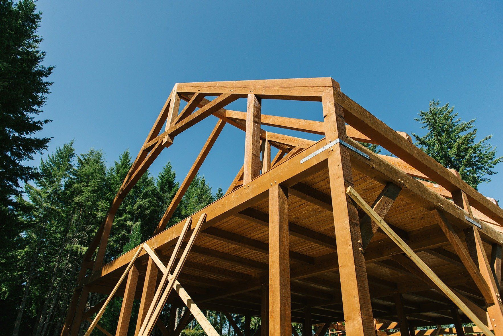 A wooden structure is being built with trees in the background.