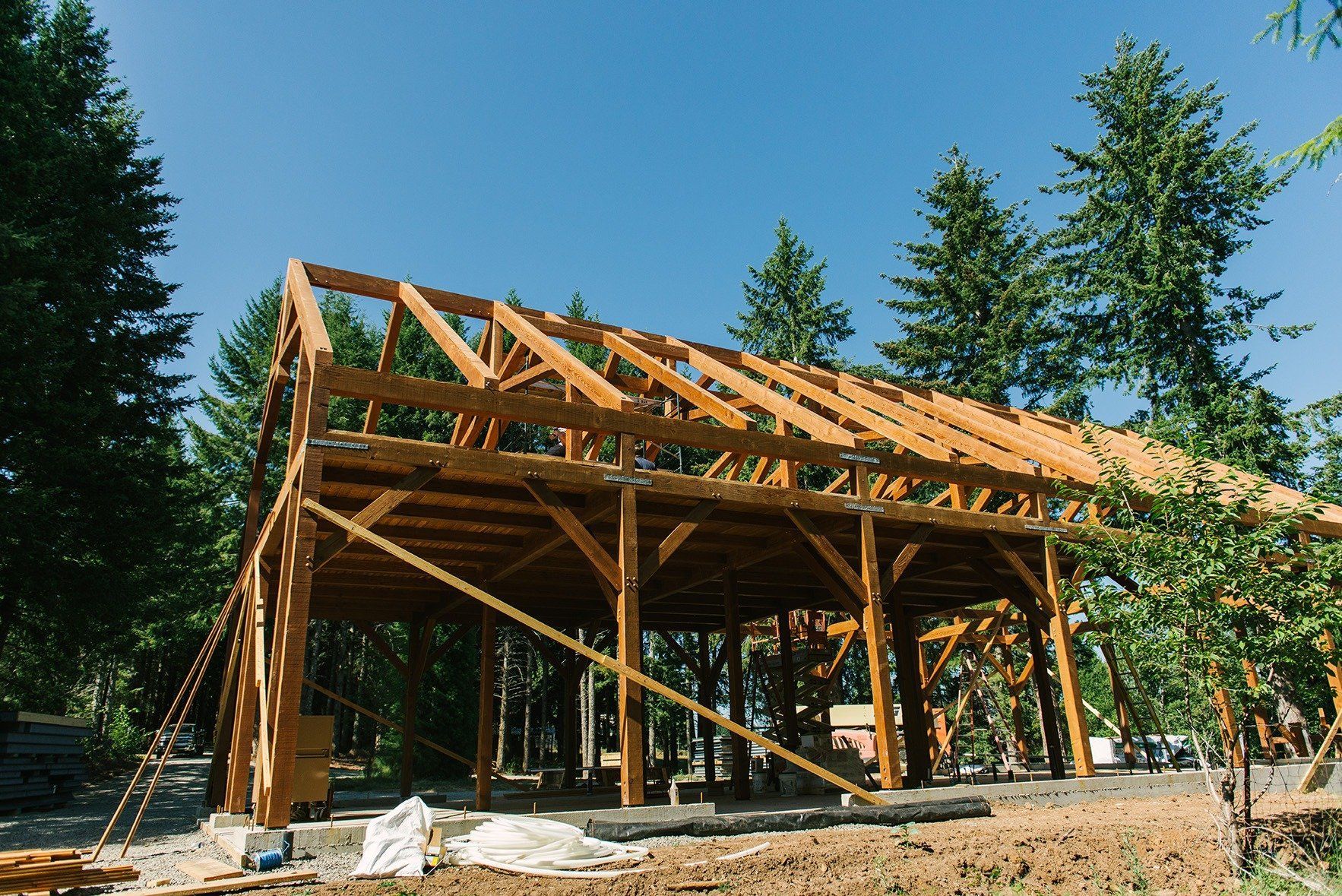 A large wooden structure is being built in the middle of a forest.