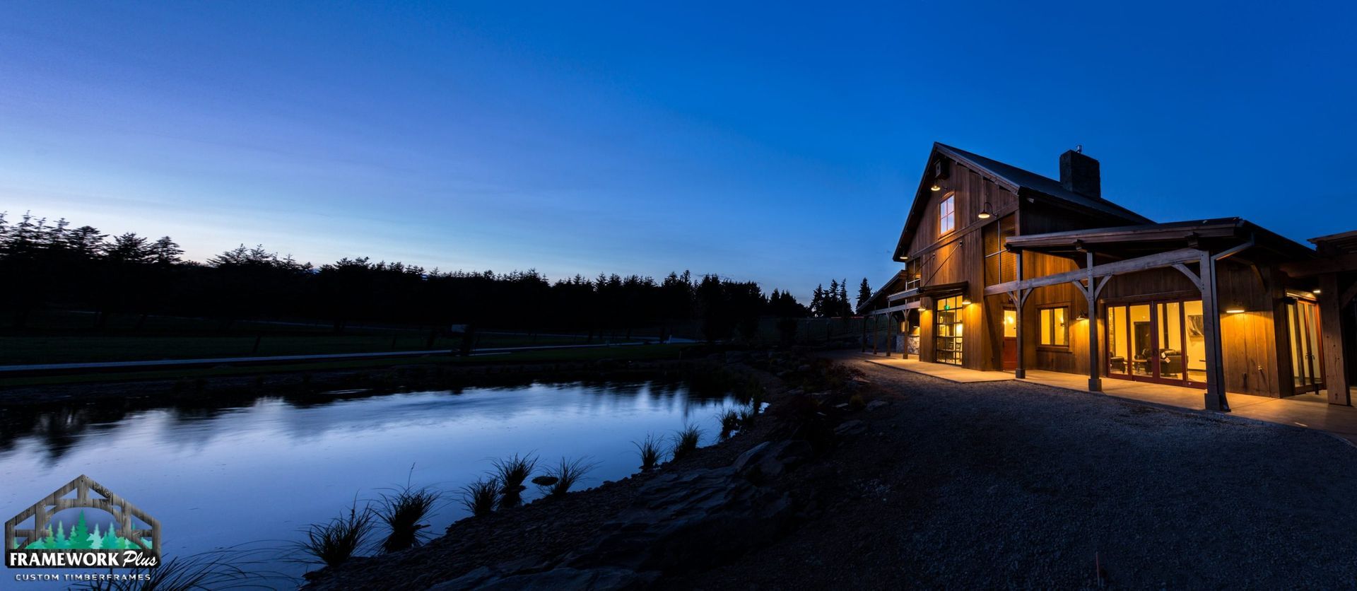 A large house is lit up at night next to a lake.