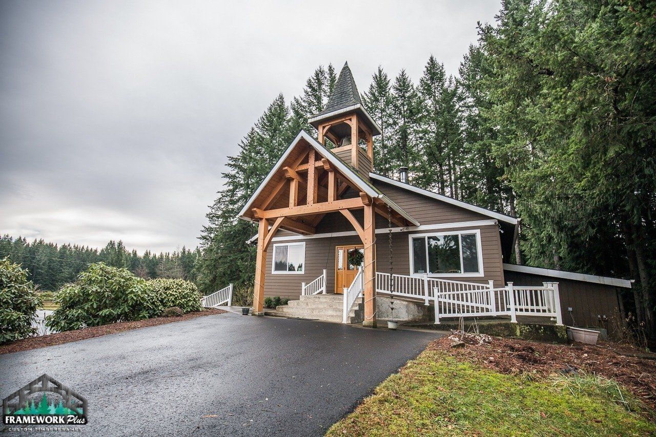 A small house with a wooden roof is surrounded by trees on a cloudy day