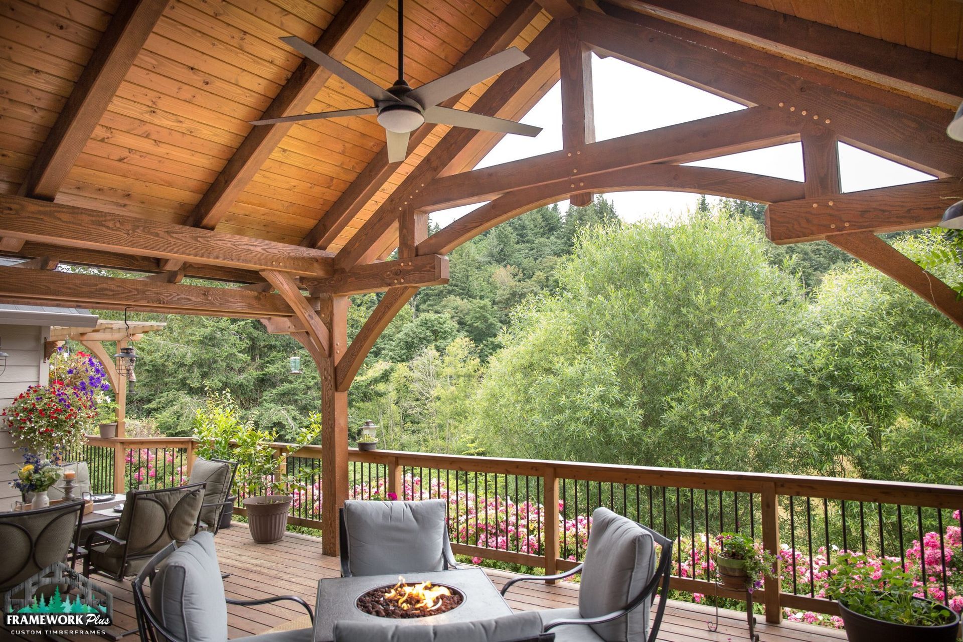 A wooden deck with a table and chairs and a ceiling fan.
