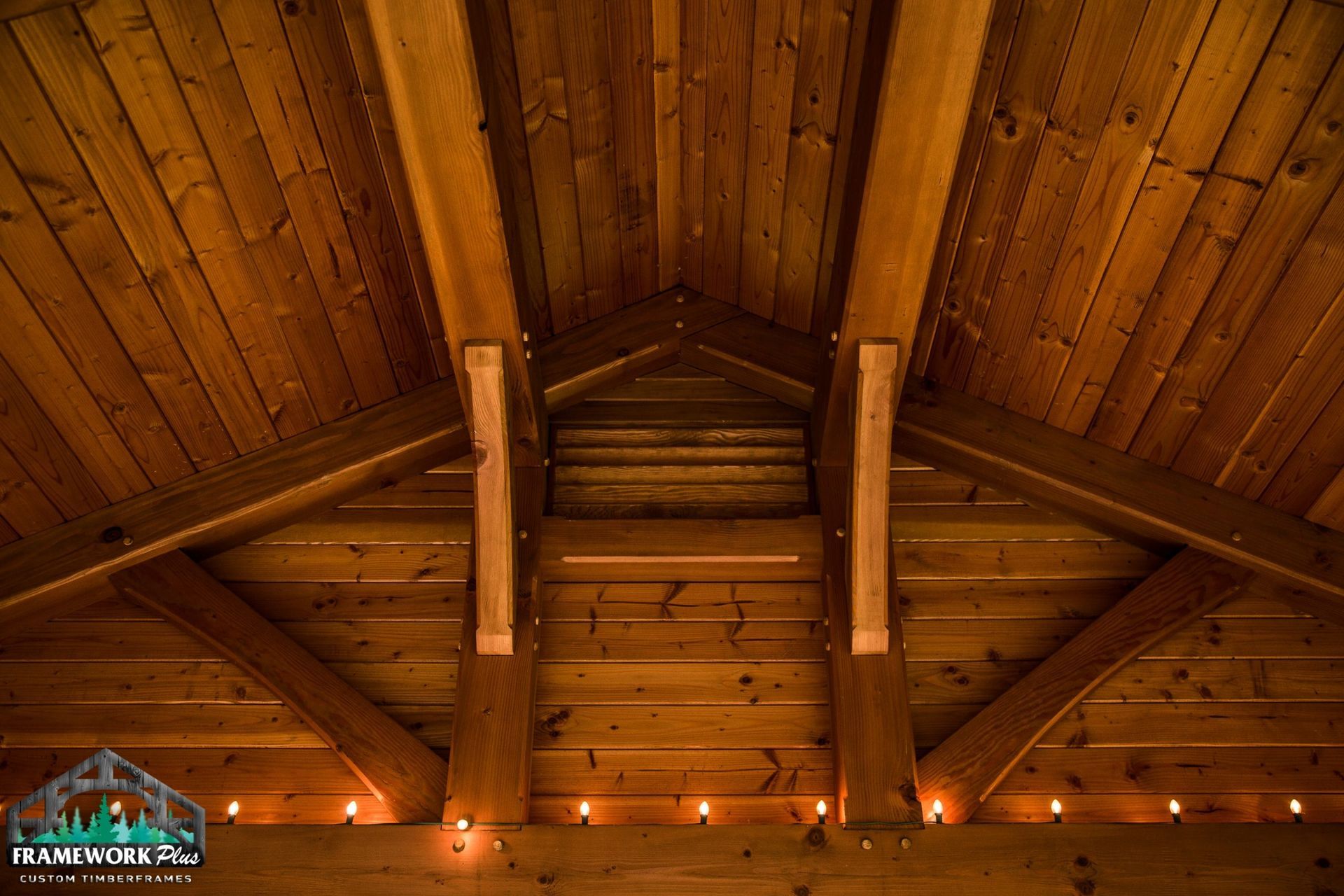 The ceiling of a wooden building with candles hanging from it.