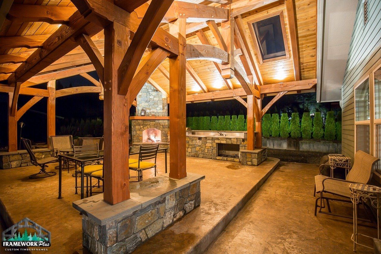 A patio with a wooden structure and a fireplace at night.