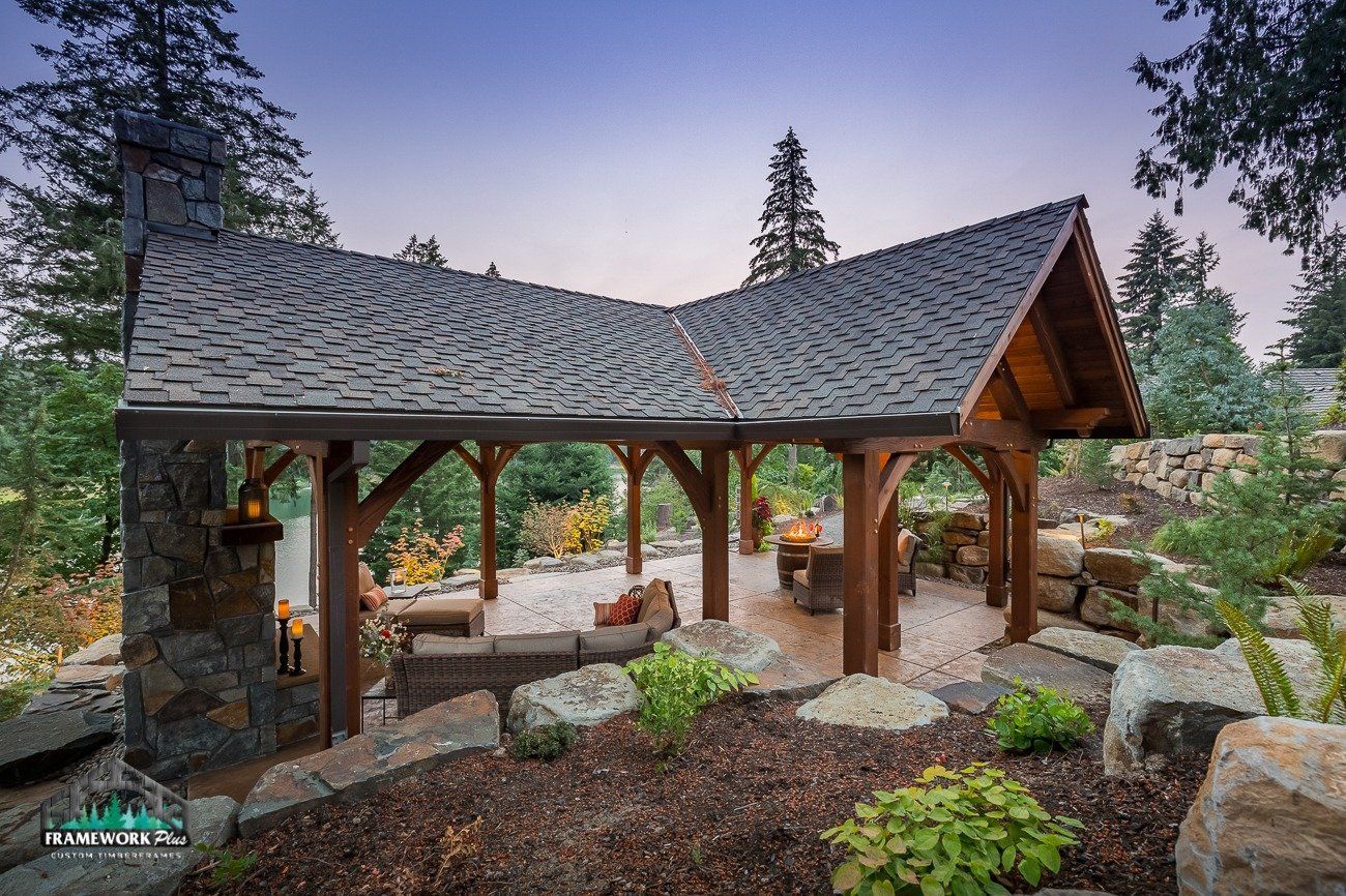 A wooden pavilion with a slate roof is surrounded by rocks and trees.