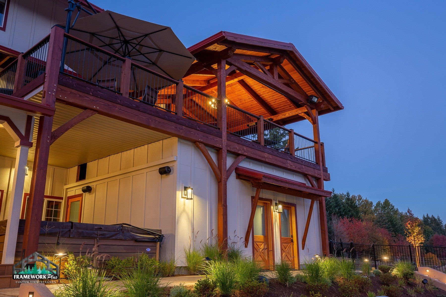 A large white house with a wooden deck and umbrella.