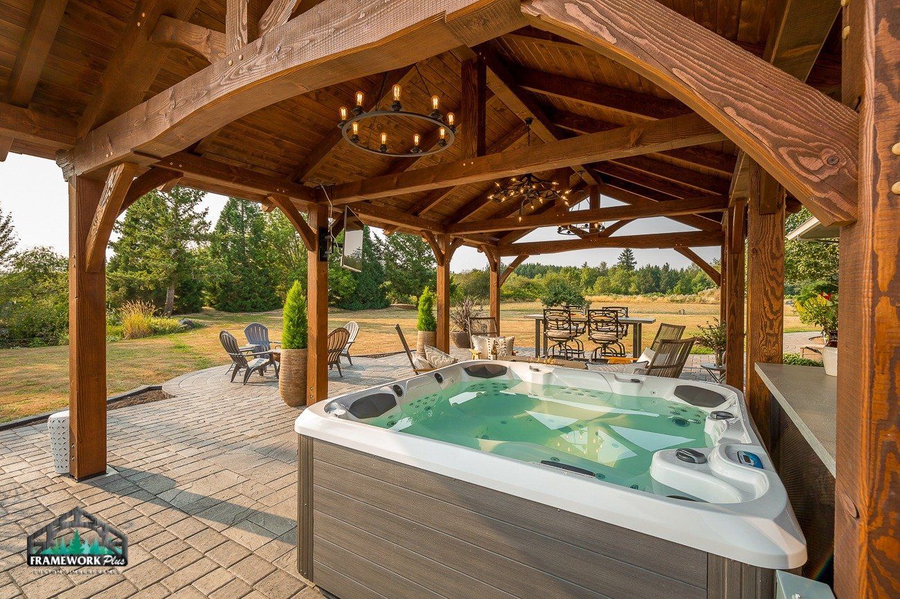 A hot tub is sitting under a wooden gazebo.