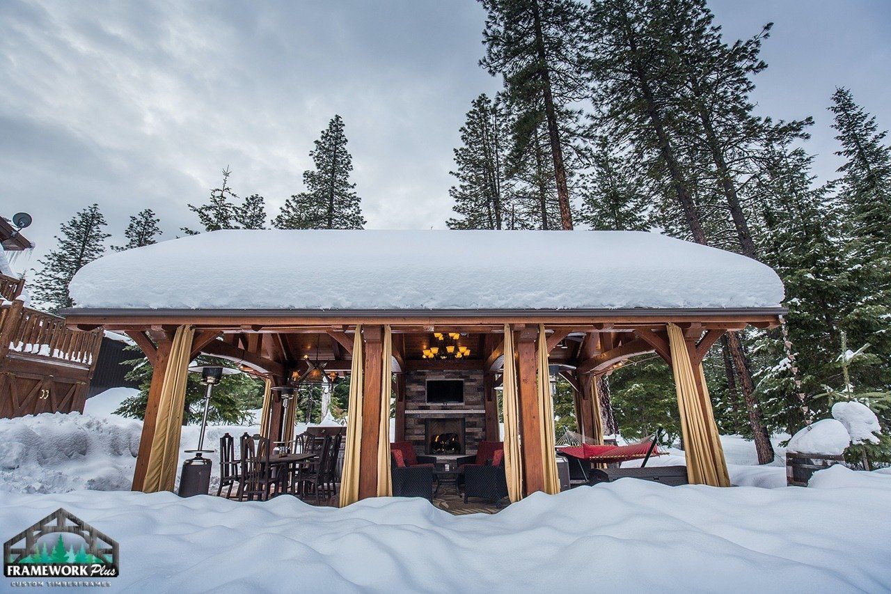 A wooden structure covered in snow with trees in the background