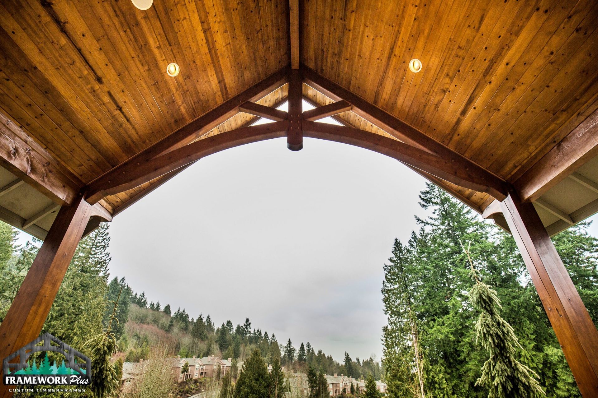 Looking up at the ceiling of a wooden structure with trees in the background.