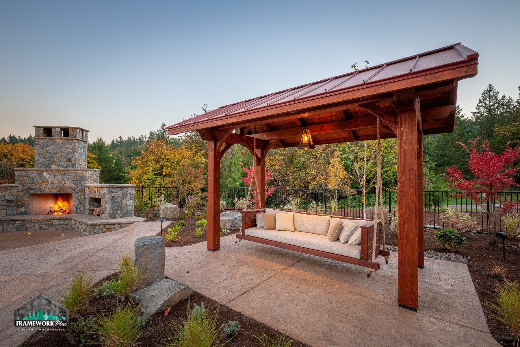 A wooden swing is sitting under a wooden gazebo.