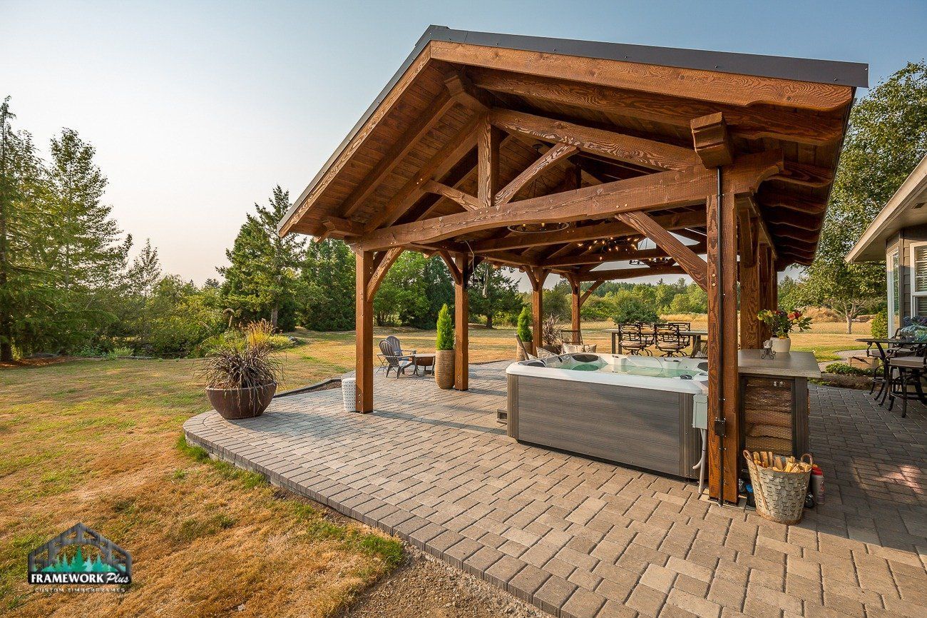 A wooden gazebo with a hot tub underneath it.