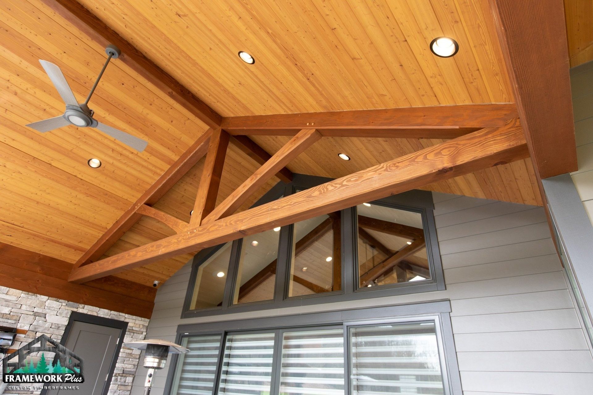 The ceiling of a house with wooden beams and a ceiling fan.