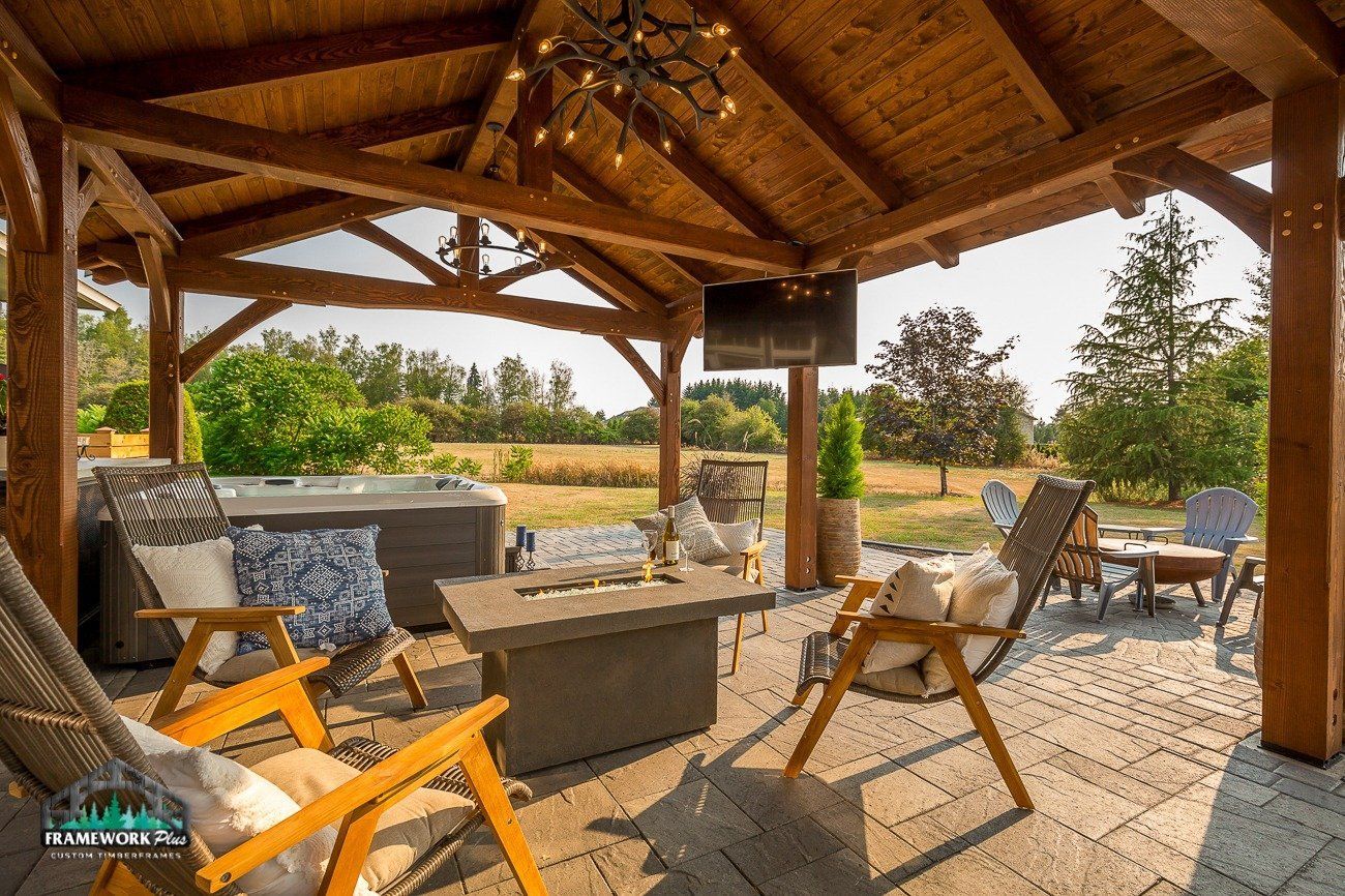 A wooden gazebo with a fire pit , chairs , and a hot tub.