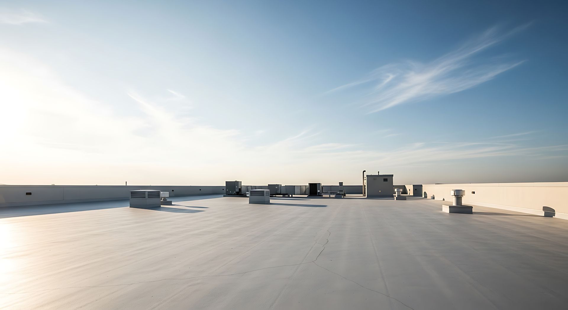 Rooftop with skylight structures under a clear blue sky at sunrise or sunset.