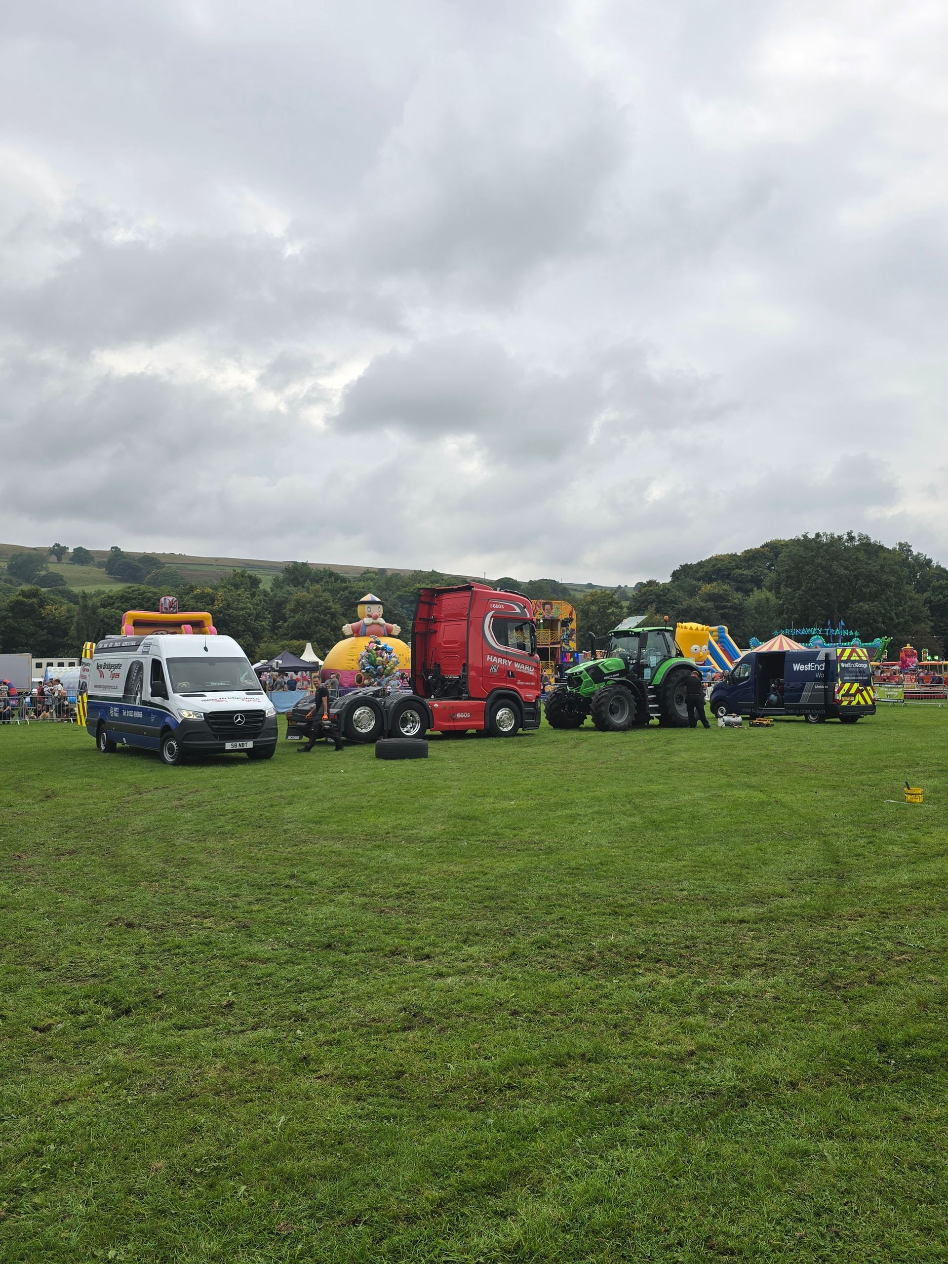 A row of trucks and tractors are parked in a grassy field.