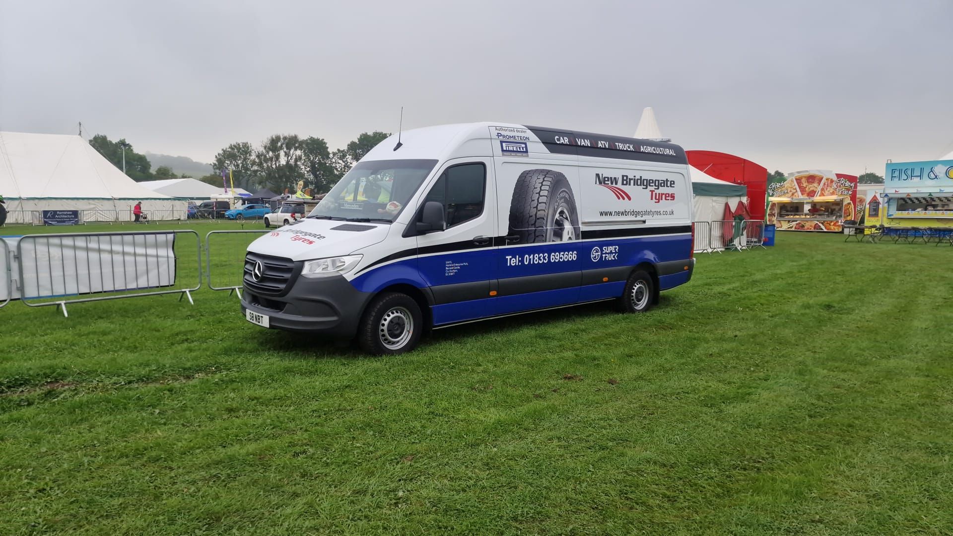 A white and blue van is parked in a grassy field.