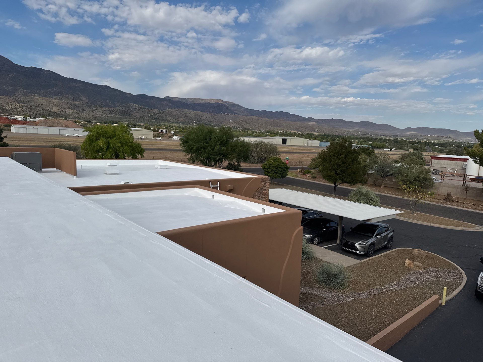 Aerial view of a complex of buildings with copper-colored roofs and a mountainous, desert landscape.