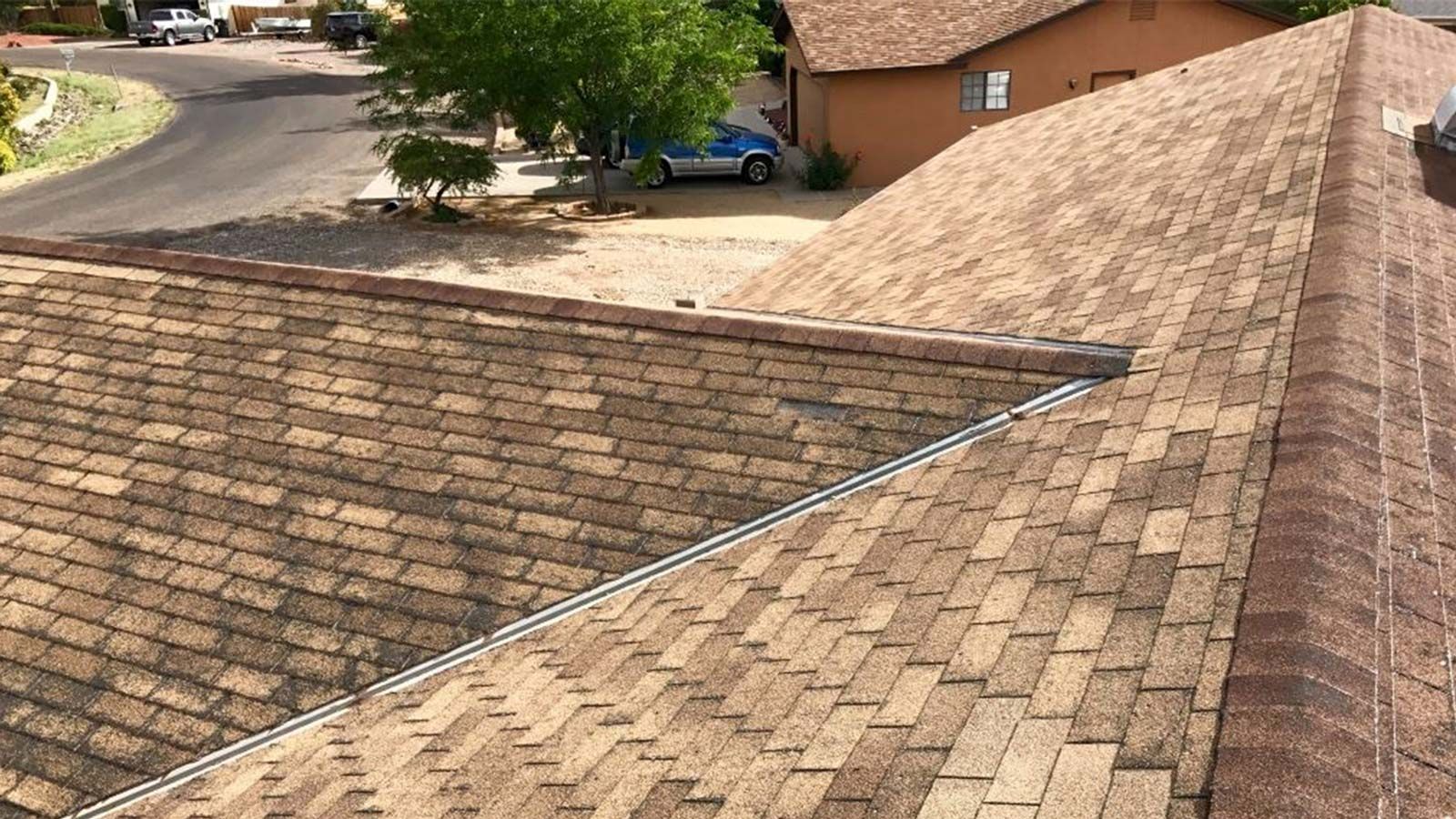 Close-up of a brown shingled roof with two skylights and a small vent.