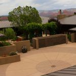 Terrace with stone planters, a tree, and a view of distant red canyon cliffs.
