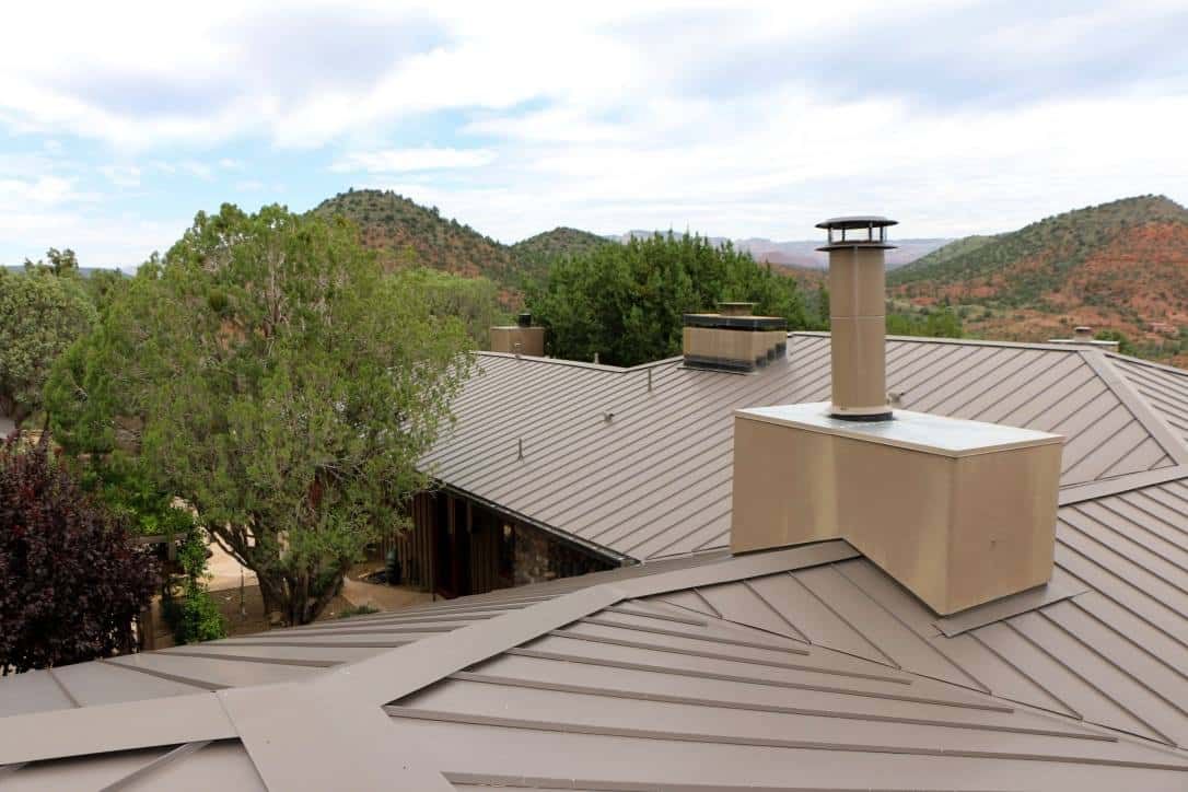 A metal roof with a chimney and a view of mountains and trees.
