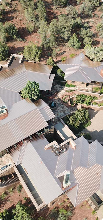 Overhead view of several buildings with a complex roofline nestled among trees and hills.