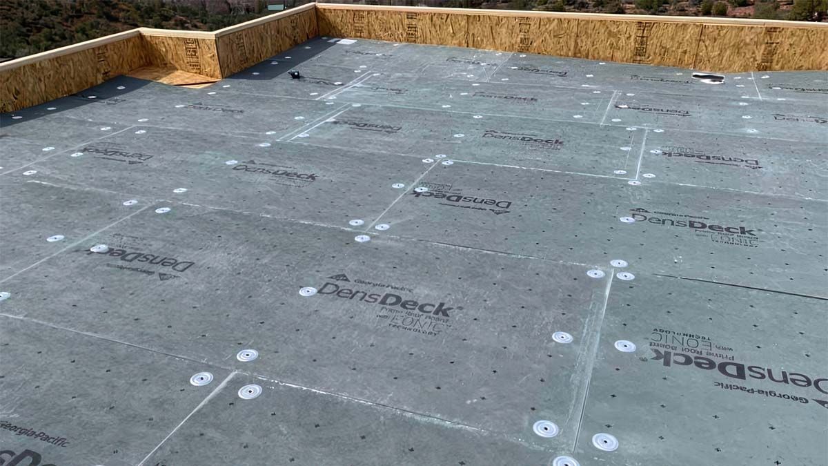 Gray roofing material installed on a wood deck, secured with white fasteners.