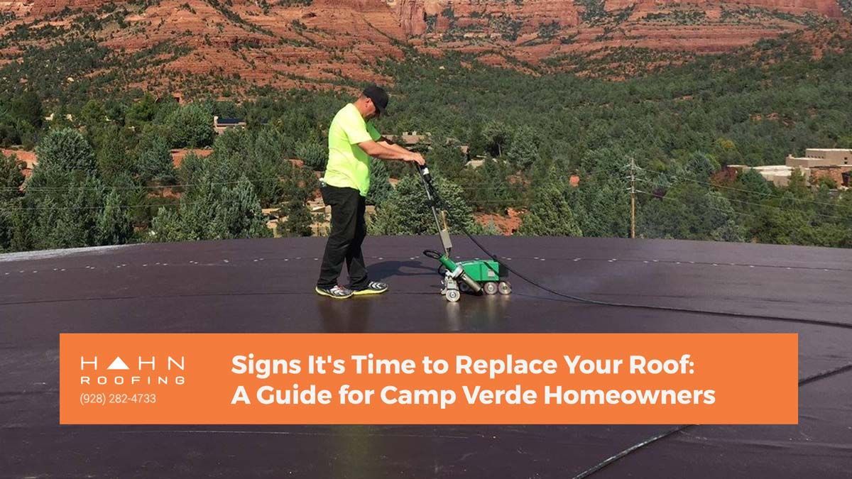 Man on a dark roof with equipment; Camp Verde mountains in the background. 