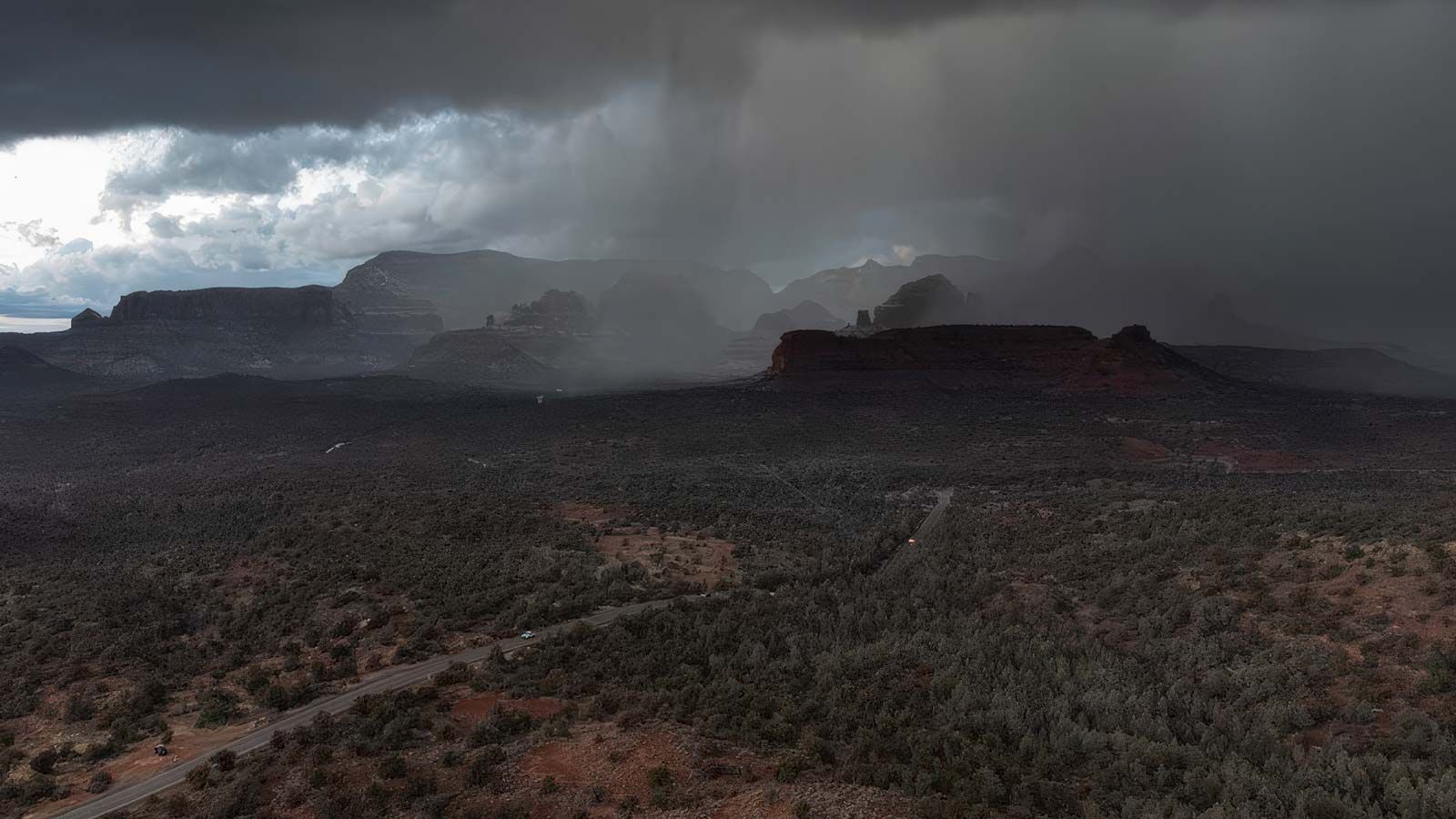 Rainstorm over red rock formations and desert landscape.