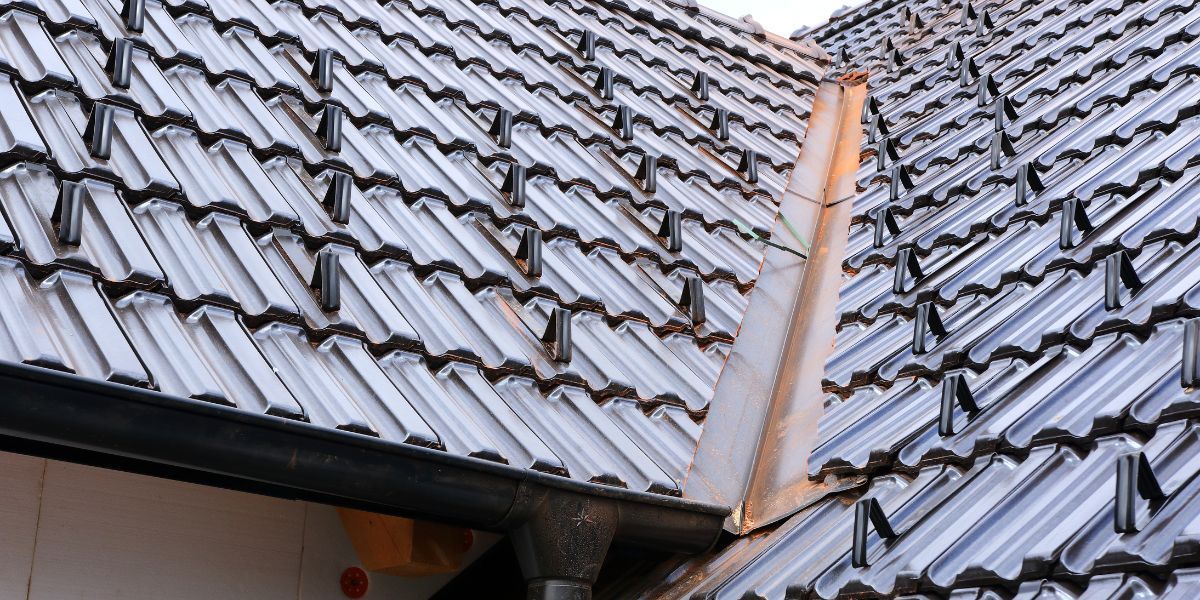Close-up of a tiled roof with a metal gutter and flashing, possibly newly installed.