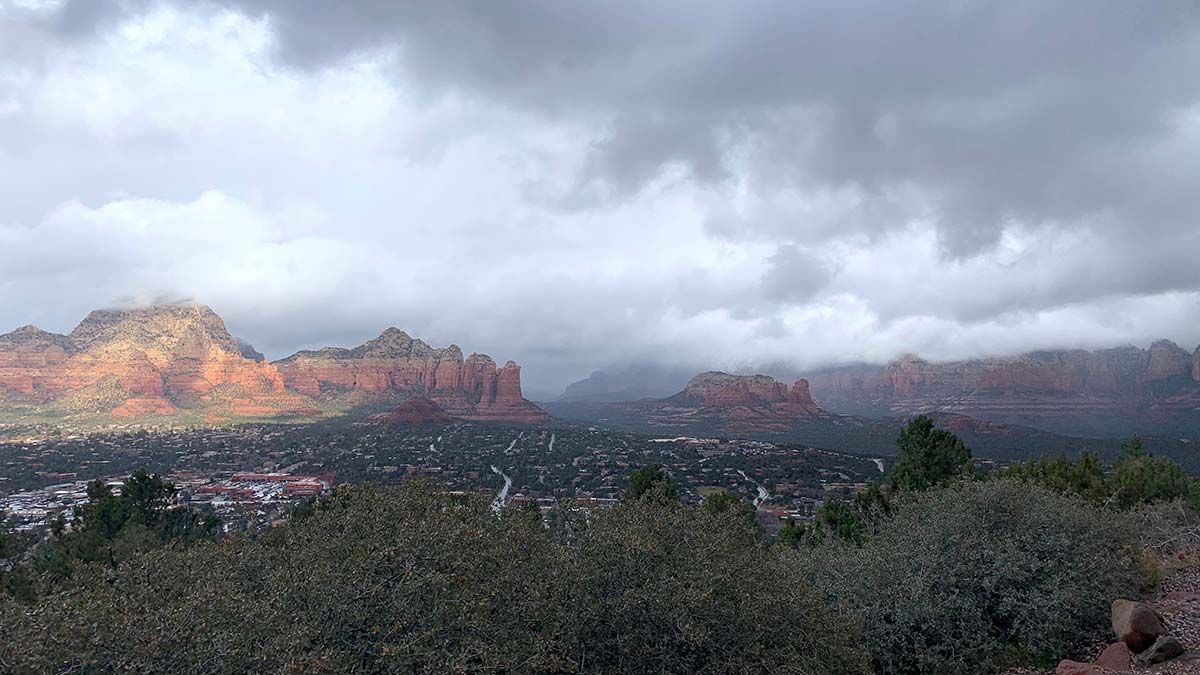 Red rock landscape with a town nestled below cloudy sky.