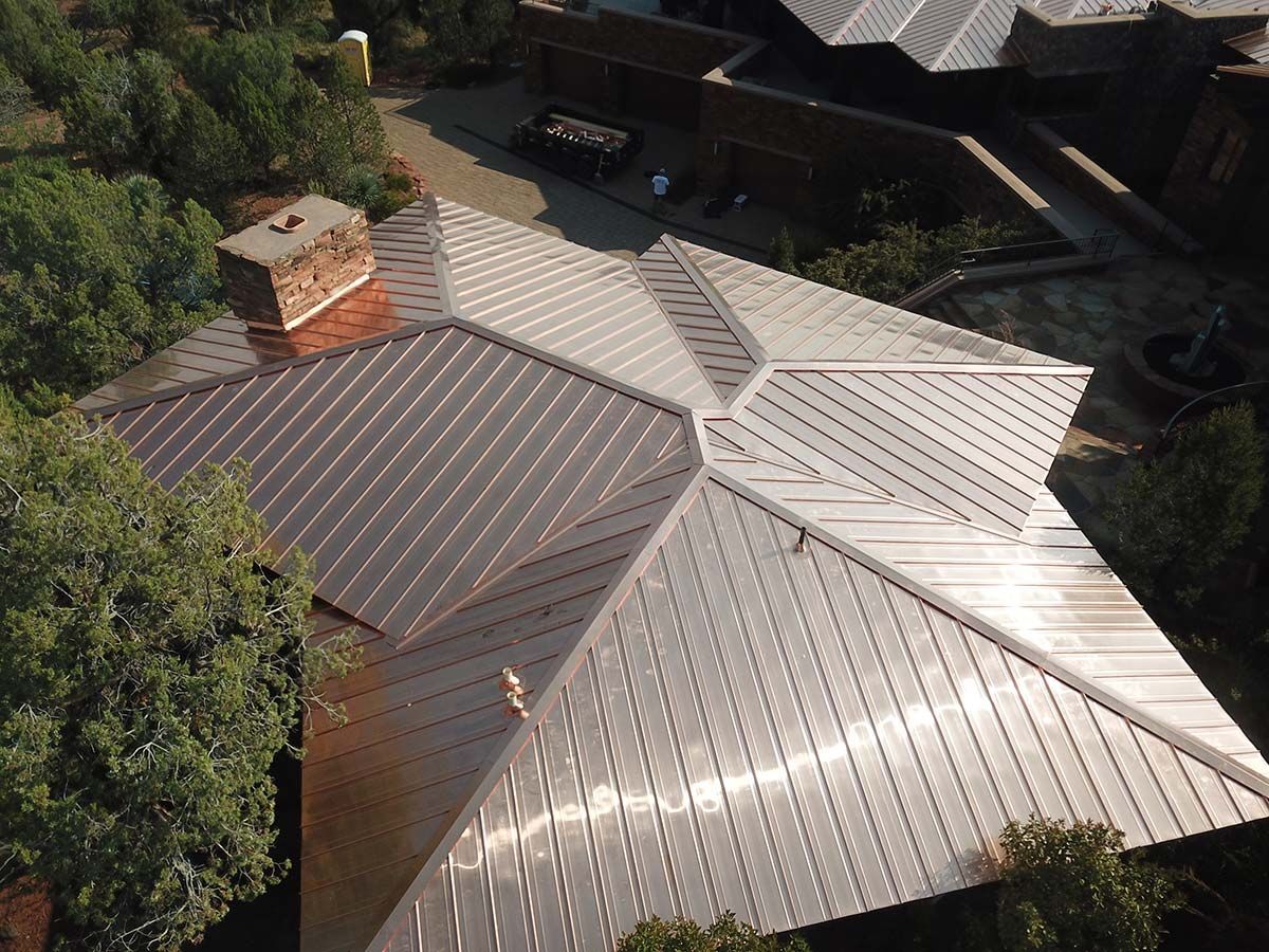 Metal roof on a multi-angled building, viewed from above, surrounded by trees.