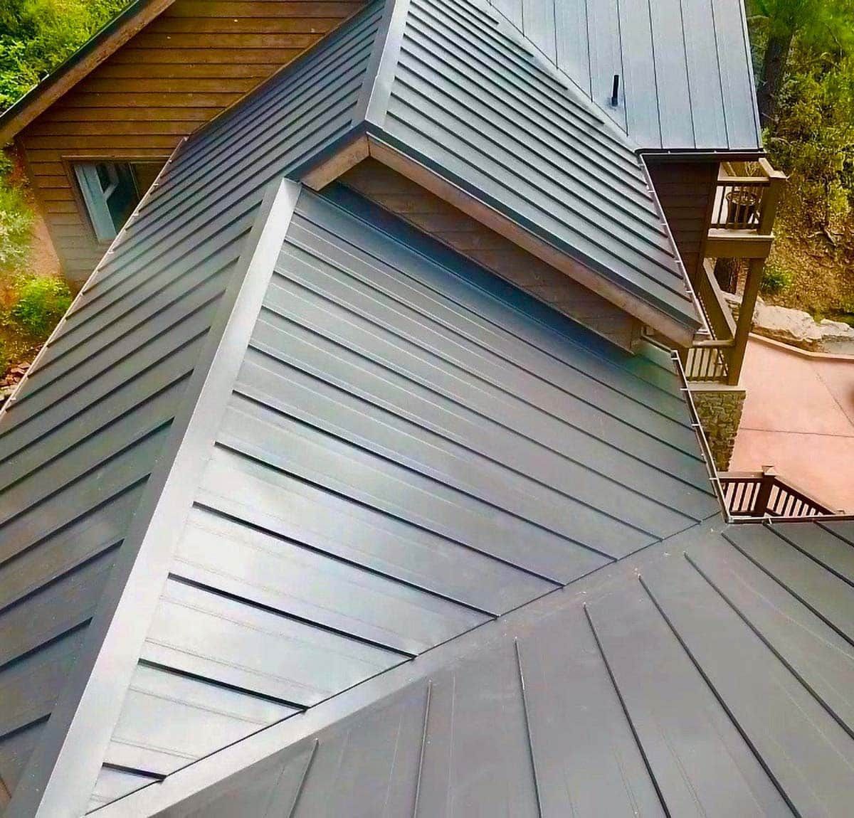 Metal roof with red trim and chimney, set against a mountainous backdrop.