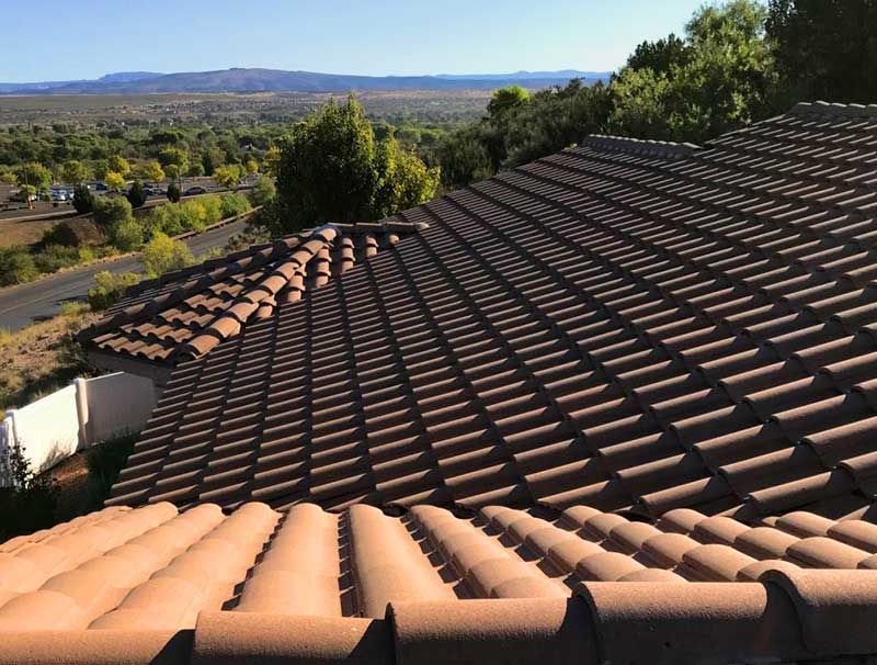 Brown tile roof with a scenic landscape of trees and hills in the background on a sunny day.