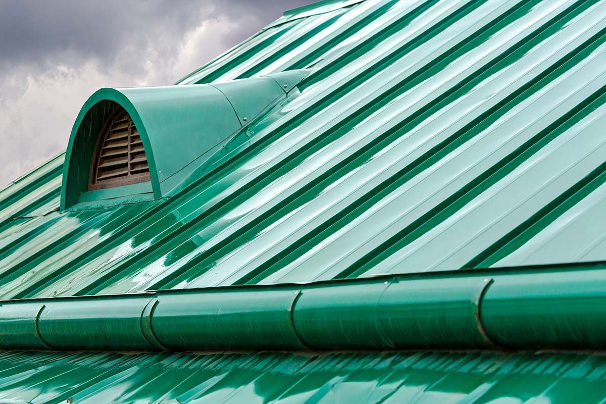 Green metal roof with a curved vent and matching gutter.