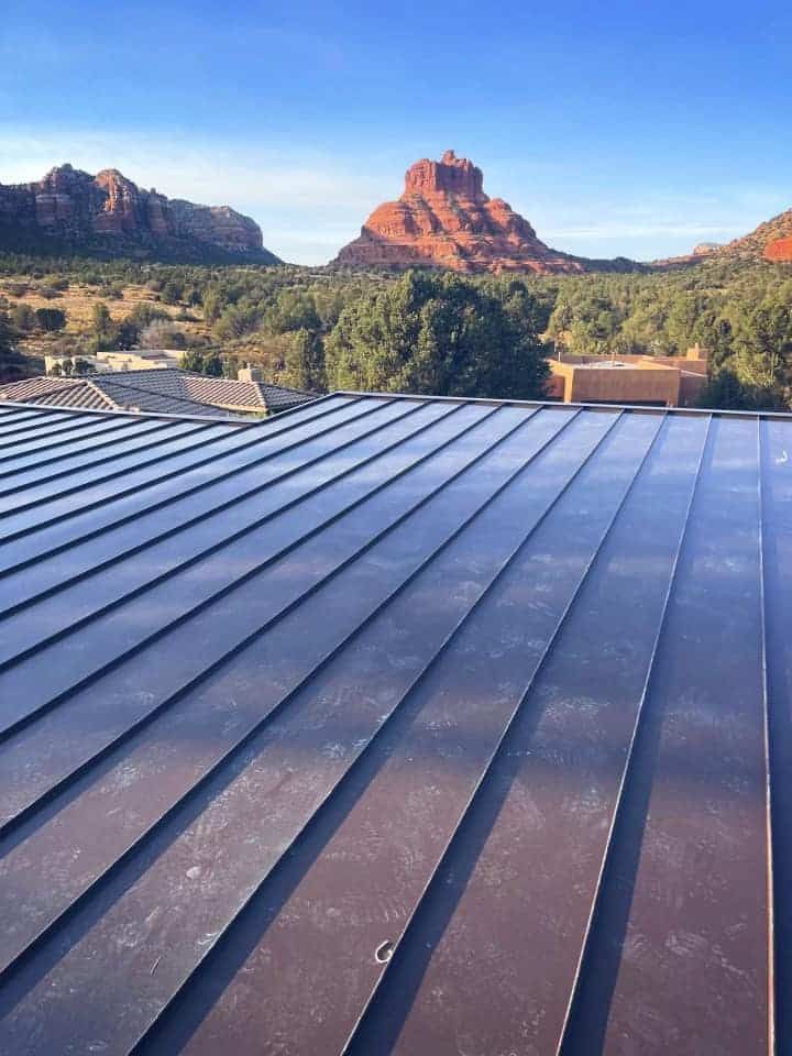 View of a metal roof with a mountain landscape in the background, blue sky.