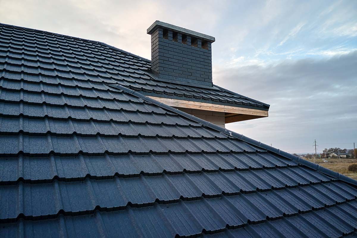 A shingled roof with a copper pipe, set against a red rock mountain backdrop.